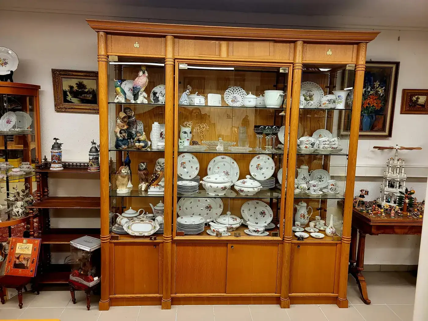 Vitrine mit Manufakturporzellan, Tafelgeschirr und Kristallgläsern im Antik-Laden